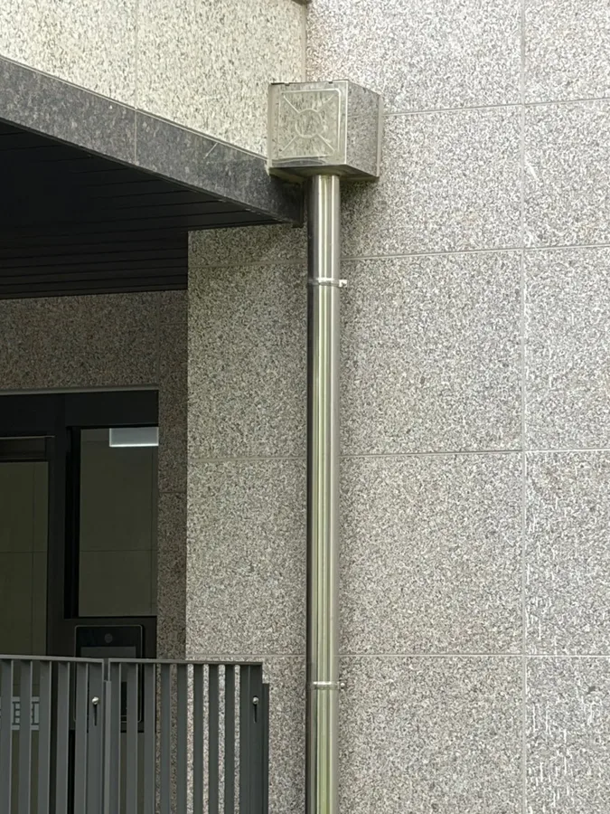 화강석 외벽 모서리에 설치된 스테인리스 우수관 근접 사진