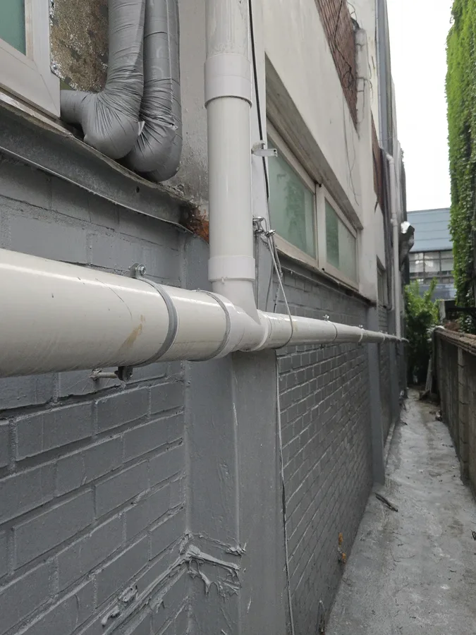 골목 담벼락에 설치된 흰색 PVC 우수관 사진